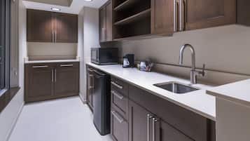 A modern kitchen with dark wooden cabinets, stainless steel appliances, and a white countertop.