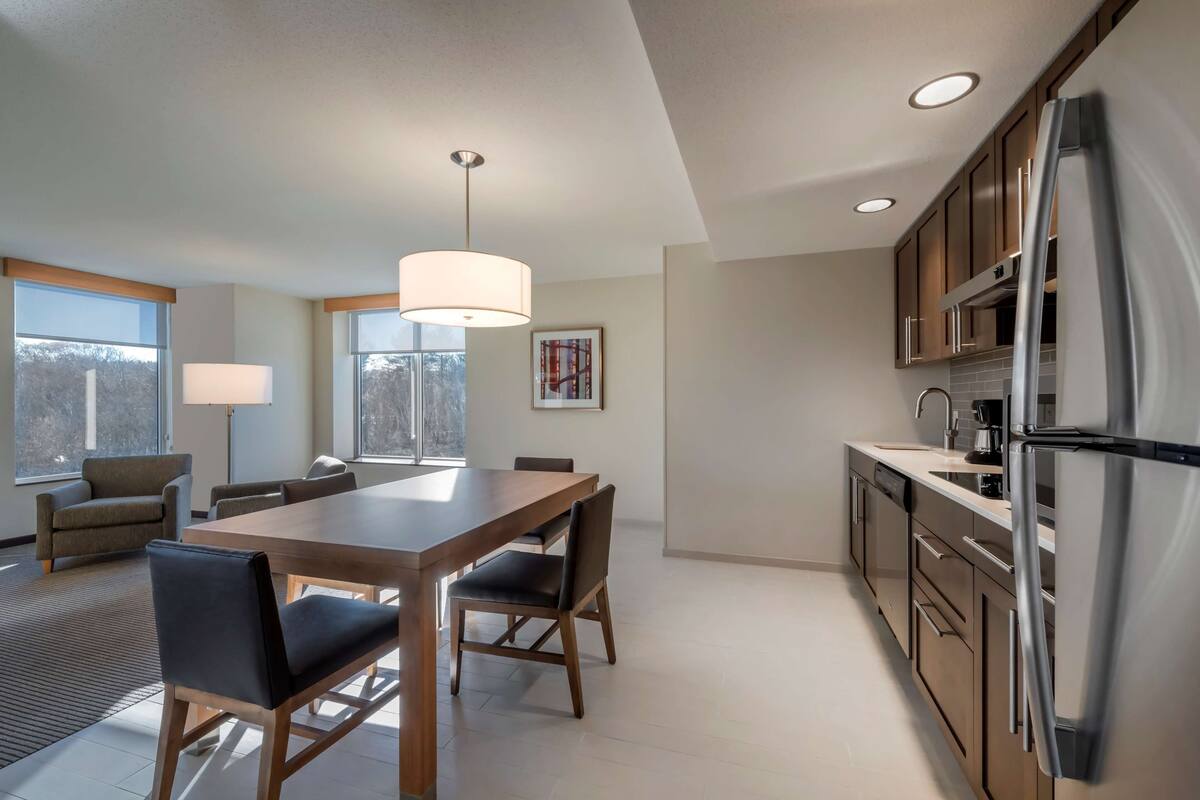 Una cocina moderna con una gran mesa de comedor, sillas y un refrigerador.