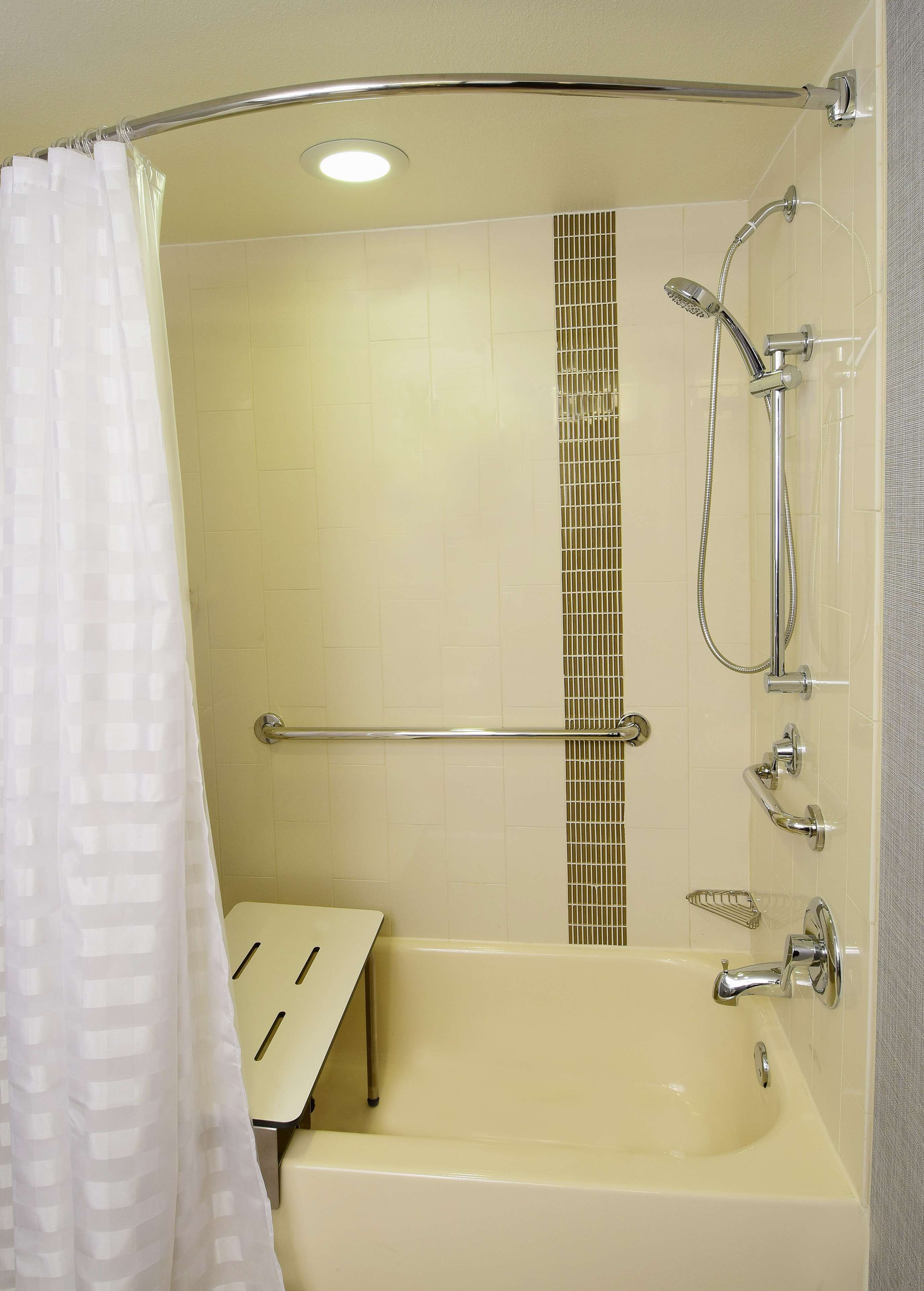 A bathroom with a bathtub, shower, and grab bar.