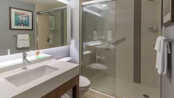 A modern bathroom with a glass-enclosed shower, a sink with a mirror, and a toilet.