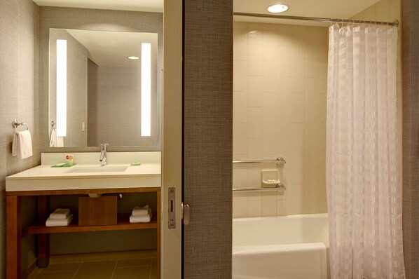 A bathroom with a white sink, mirror, and bathtub.