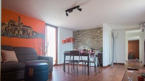 Ein modernes Wohnzimmer mit Sofa, Hocker und Essbereich mit Stühlen und einem Tisch.