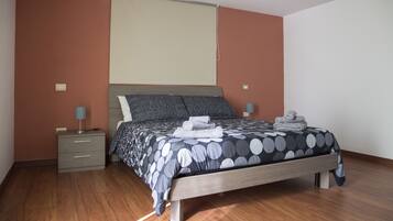 Une chambre à coucher comprenant un lit, des tables de chevet, une lampe et un écran de projection.