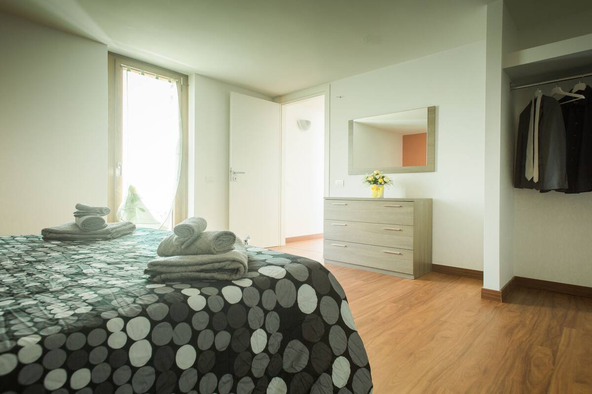 Un dormitorio con cama, cómoda, espejo y armario.