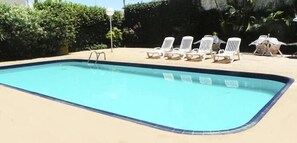 Een buitenzwembad, ligstoelen bij het zwembad