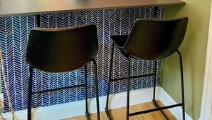 A modern kitchen with a central island, two black chairs, hanging wicker pendant lights, and a patterned backsplash. - Large, sunny 3 bedroom apartment two blocks from down town Oak Park.  (Oak Park)