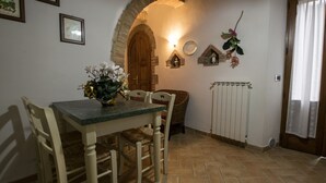 Un comedor con una mesa, sillas, un florero, un radiador y una puerta de madera.