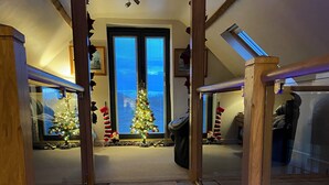Un couloir avec un tapis, des poutres en bois et un sapin de Noël.