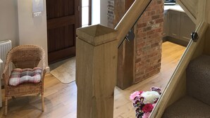 Un escalier en bois avec des rampes en verre mène à une mezzanine d’où l’on a vue sur une cuisine et une porte.