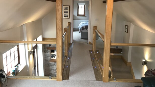 Un escalier avec des rampes en bois menant à une chambre dotée d’une fenêtre et d’un lit.