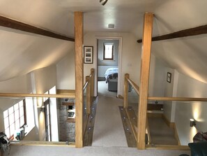 A staircase with wooden railings leading to a bedroom with a window and a bed.
