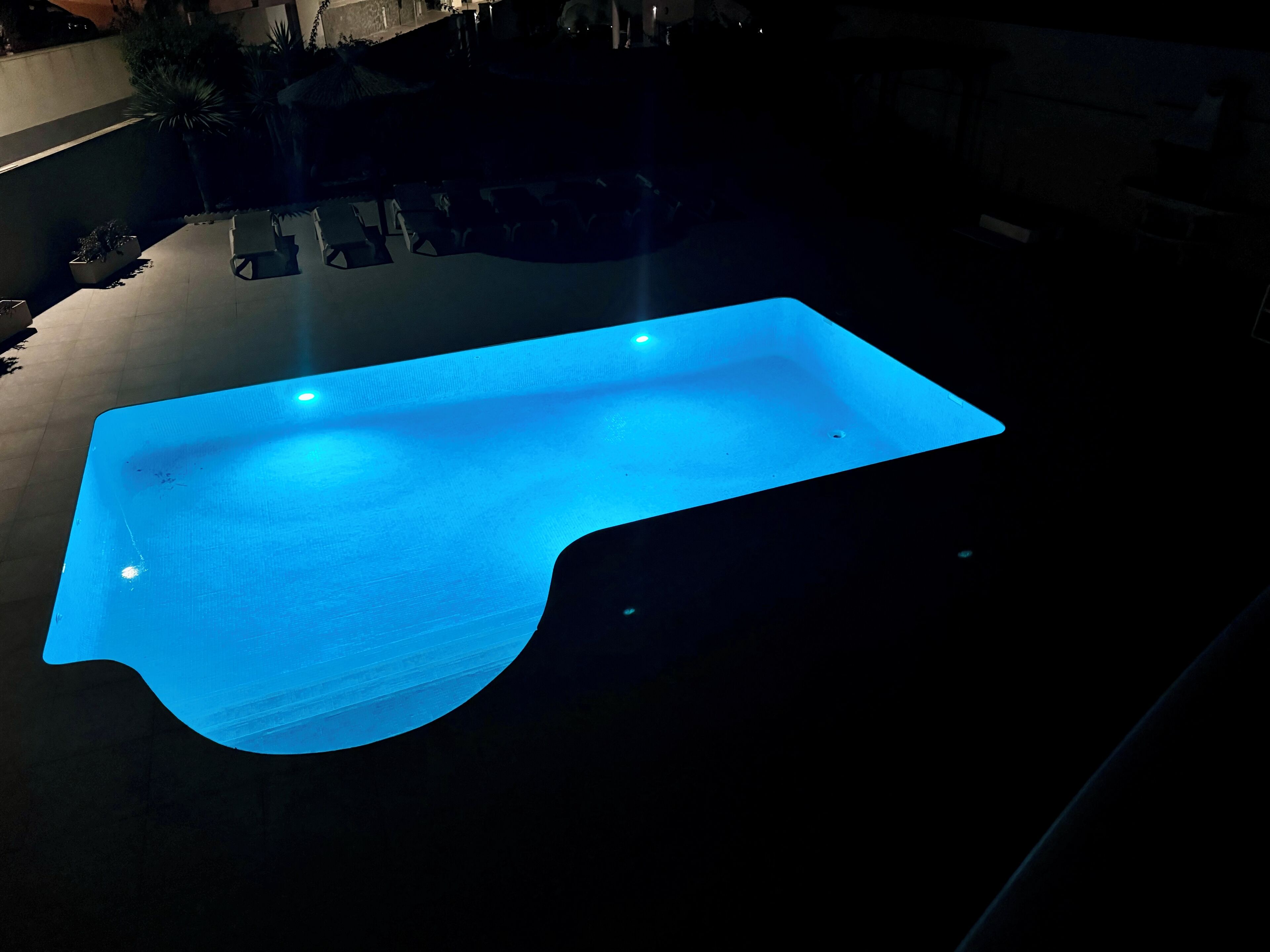 Een zwembad met een vloeiende, gebogen rand en een blauw verlicht interieur.