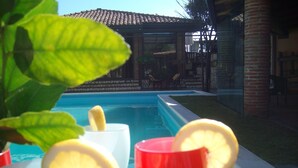A poolside view with a clear blue pool, a brick building in the background, and a table with glasses and lemon slices. - SINGLE VILLA(VILLA "SOLE" BETWEEN ETNA AND TAORMINA THE SEA TO 2 KM (ACIREALE MANGANO)