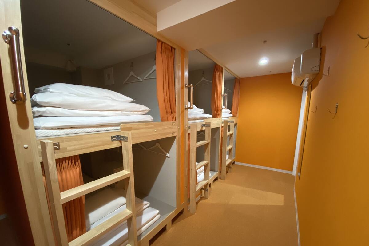 Quarto de hotel com beliches, um guarda-roupa e um espelho.
