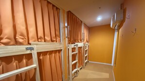 Un pasillo con literas, separadores de habitación numerados y un equipo de aire acondicionado instalado en la pared.