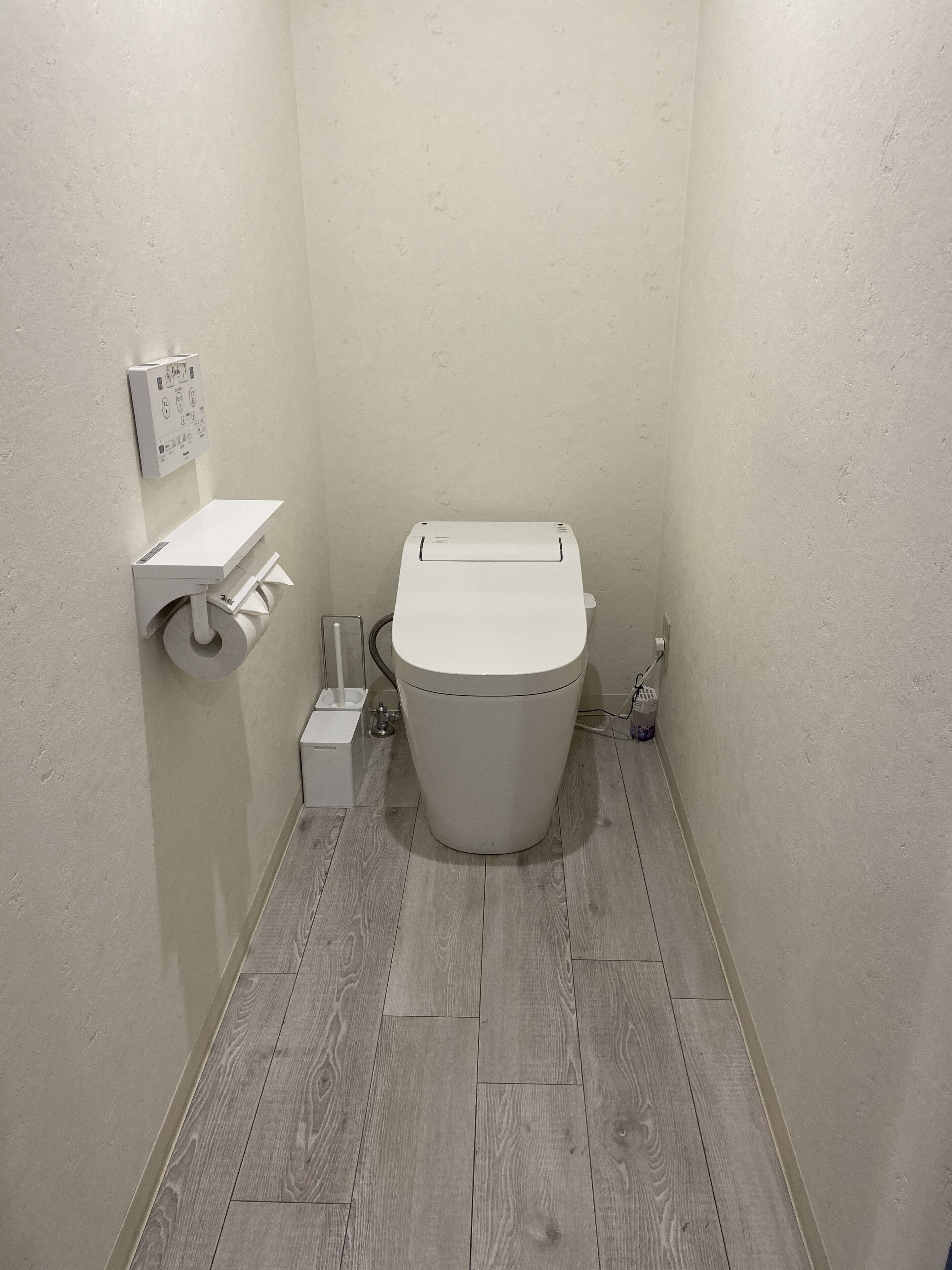 A small, modern bathroom with a toilet, a sink, and a toilet paper holder.