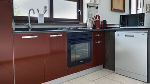 A modern kitchen with stainless steel appliances, a dishwasher, and a window above the sink. - Villa of Wings (Capo)