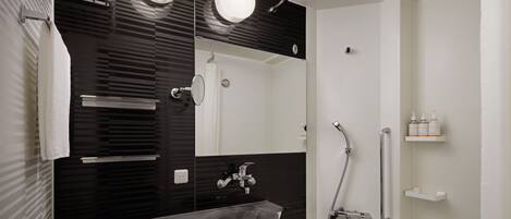 A modern bathroom with a black and white color scheme, featuring a sink, mirror, and shower.