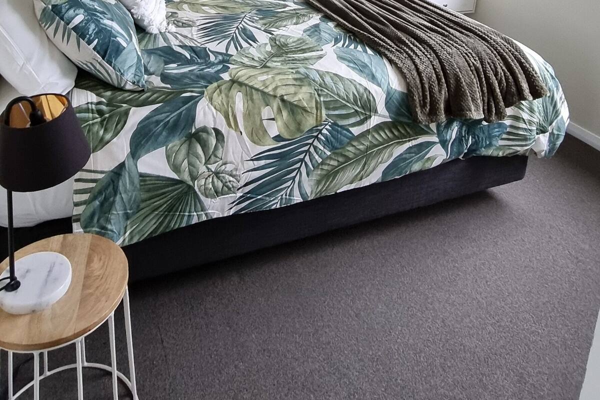 Un dormitorio con una cama, un ventilador de techo, una ventana y un cuadro abstracto verde en la pared.