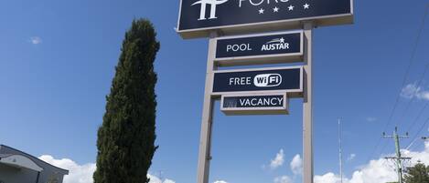 A hotel sign with amenities including a pool, free Wi-Fi, and a vacancy notice.