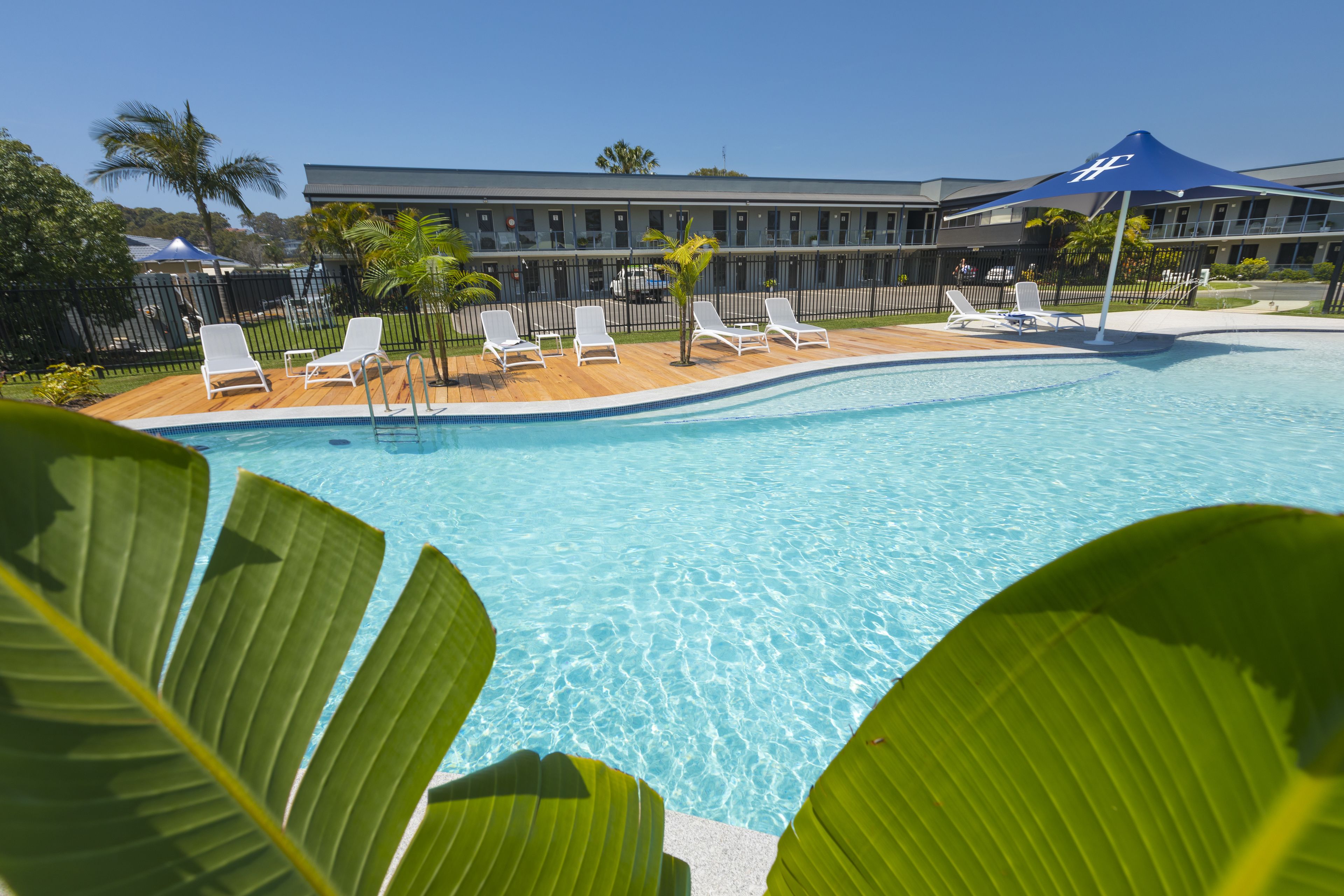 A swimming pool with lounge chairs and a building in the background.
