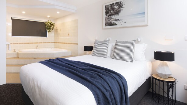 Quarto de hotel com uma cama grande, uma pia dupla e uma moldura com um quadro na parede.