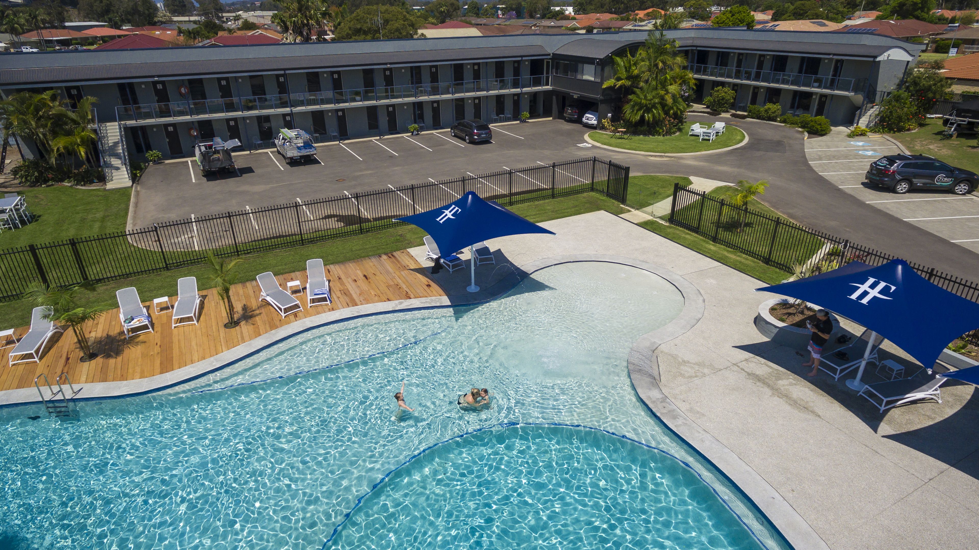 Een hotel met een zwembad, ligbedden en parasols.