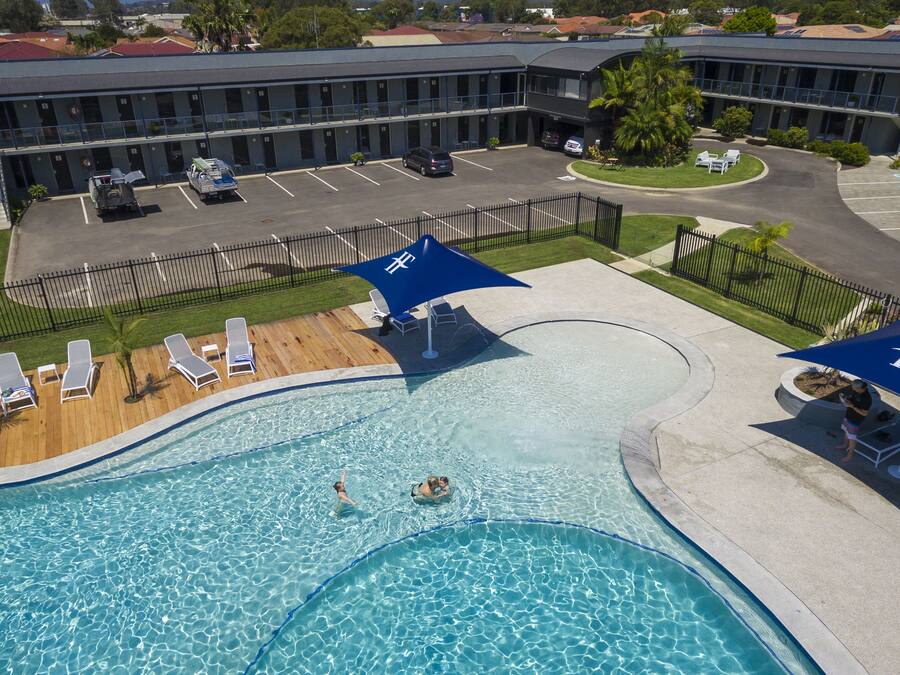A hotel with a swimming pool, sun loungers, and umbrellas.