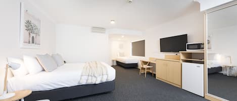 Ein modernes Hotelzimmer mit einem großen Bett, einem Schreibtisch, einem Stuhl, einem Flachbildfernseher und einer Mikrowelle.