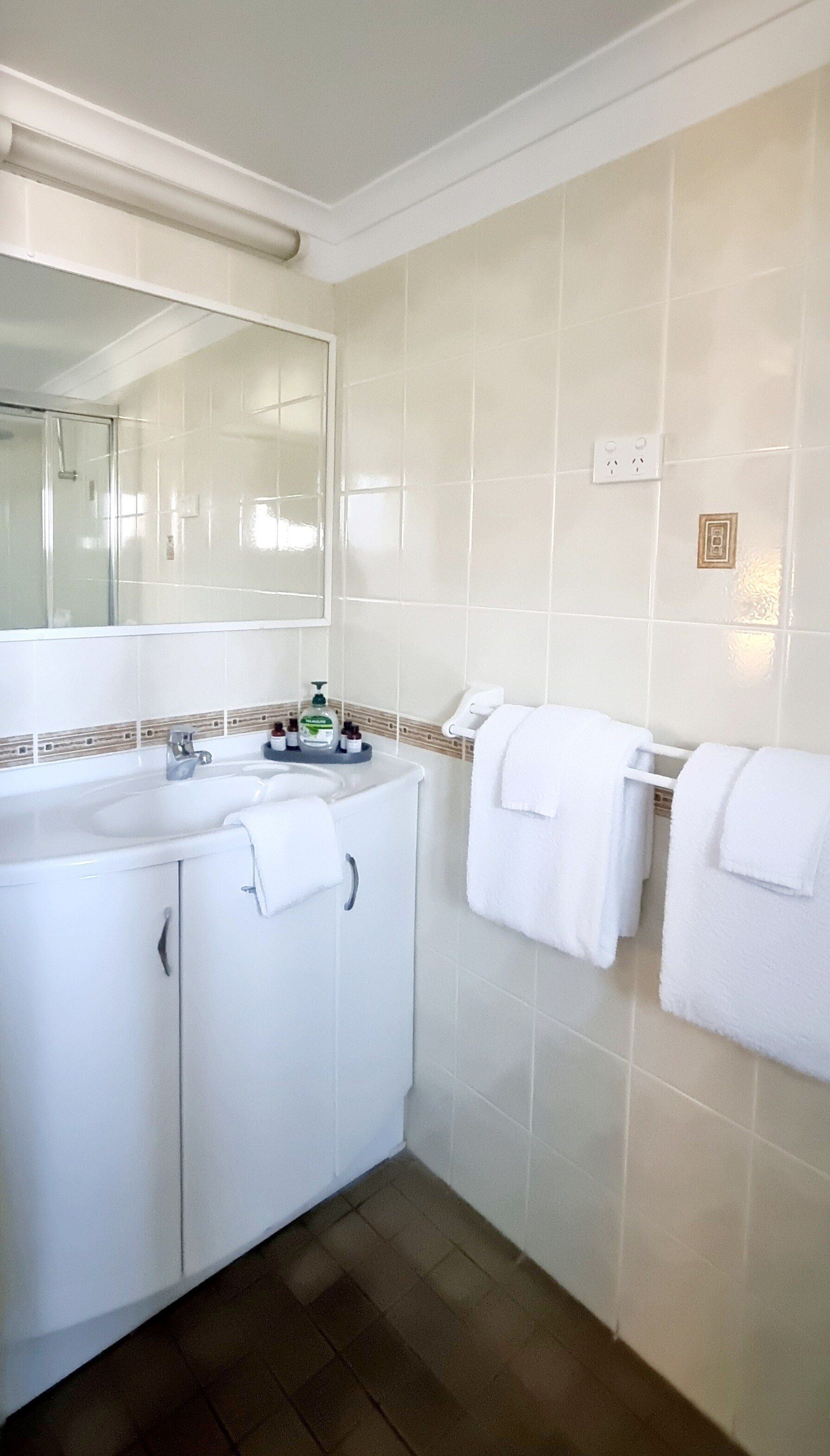 A bathroom with a white sink, mirror, and two towel racks with white towels.