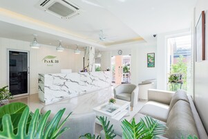 Un hall d’hôtel moderne avec un comptoir d’accueil en marbre, des sièges confortables et une vue sur l’espace extérieur.