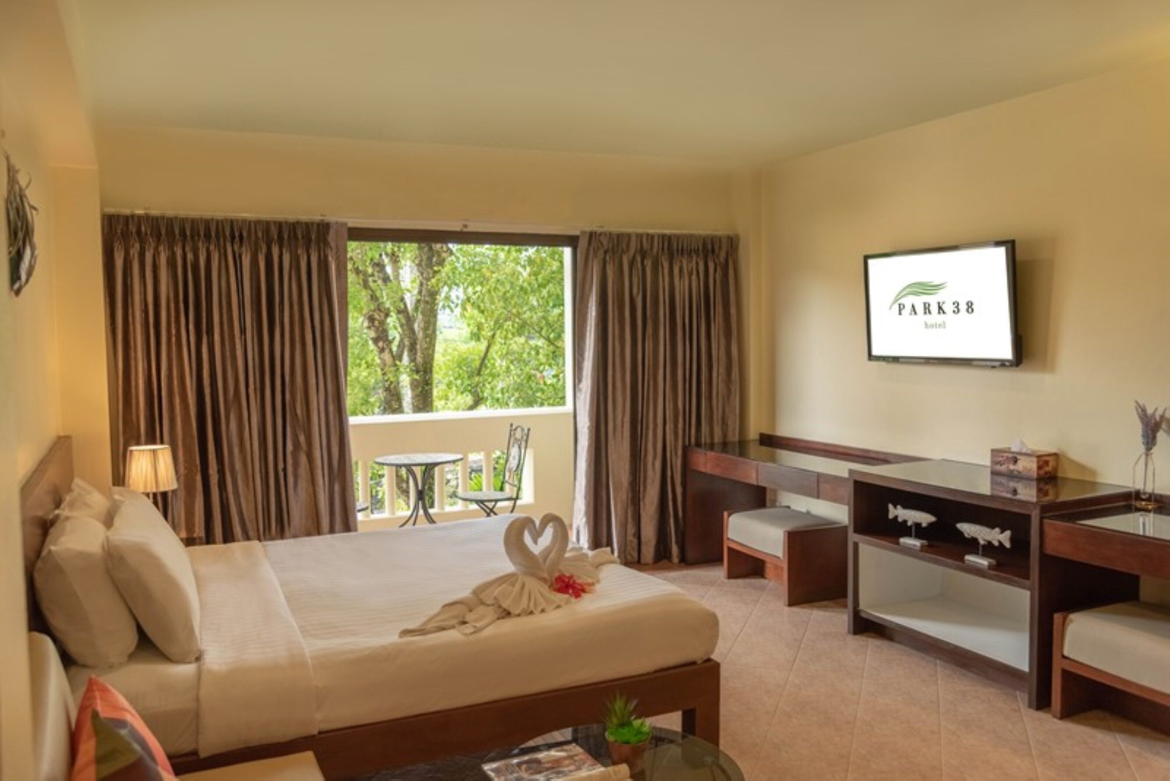 Habitación de hotel con cama, escritorio, silla, televisor y balcón con mesa y sillas.