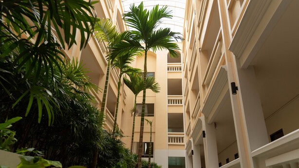 A multi-story hotel atrium with a central open space surrounded by balconies and lush greenery. - Park 38 Hotel (Wichit)