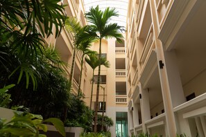 A multi-story hotel atrium with a central open space surrounded by balconies and lush greenery. - Park 38 Hotel (Wichit)