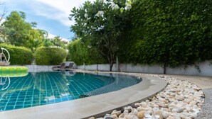A swimming pool with a pebble border, surrounded by greenery and a white wall. - Park 38 Hotel (Wichit)