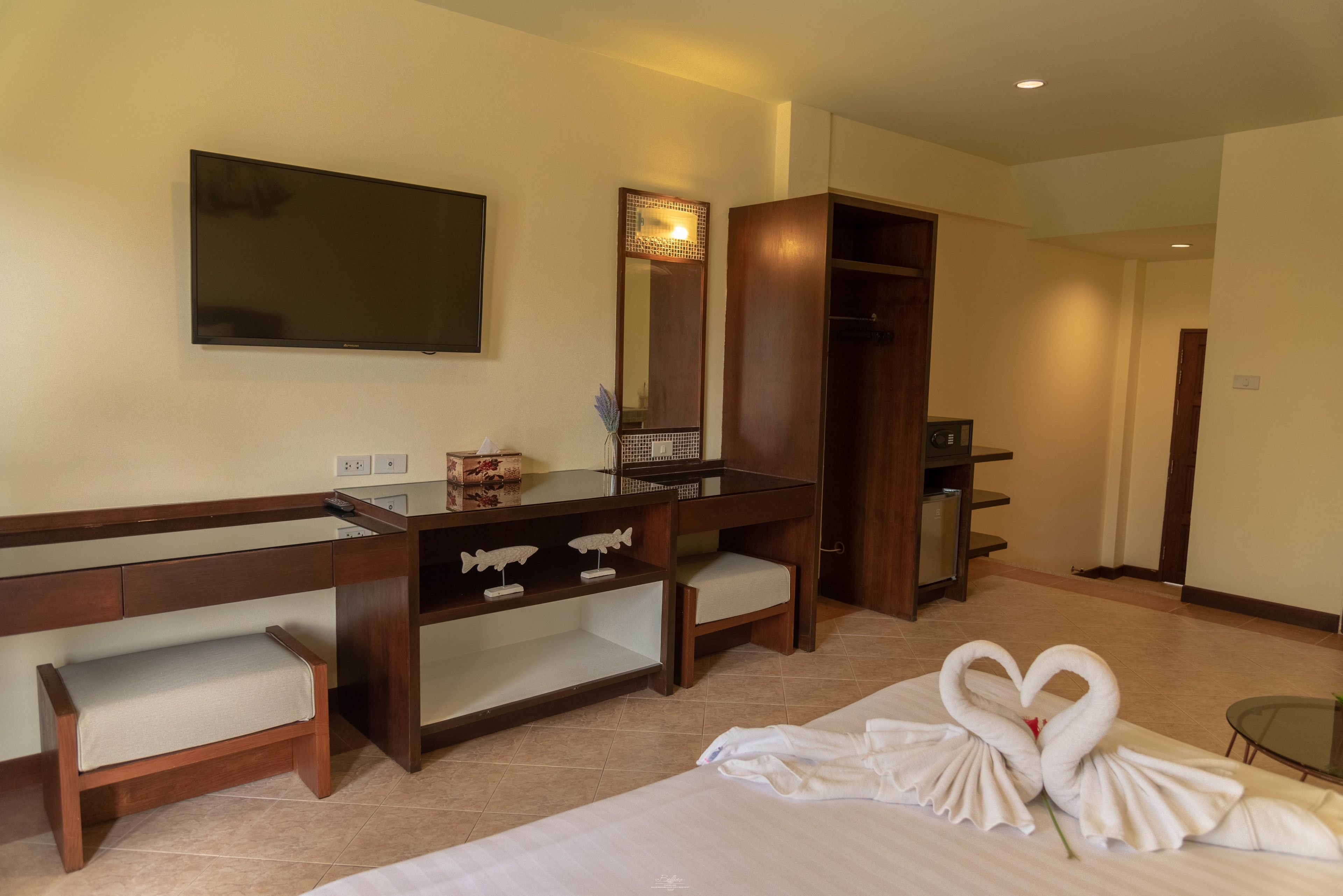 Quarto de hotel com cama, escrivaninha com espelho, cômoda e guarda-roupa.