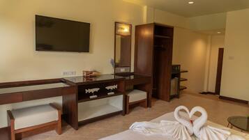 Quarto de hotel com cama, escrivaninha com espelho, cômoda e guarda-roupa.