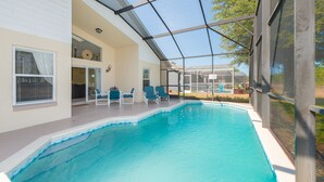 Ein überdachter Außenpool mit Liegestühlen und einer patioartigen Sitzgruppe mit Glasfassade.