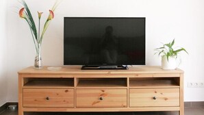 Un mueble bajo de madera para televisor con pantalla plana, dos cajones y dos macetas.