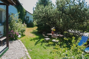 A garden with a wooden table and chairs, a bench, and a blue striped chair. - Beautiful, spacious apartment at the gates of the Hanseatic city of Rostock  (Lambrechtshagen)