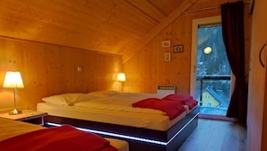 Una camera in una baita di legno con due letti, un balcone e vista all'esterno.
