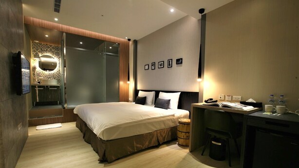 Une chambre d’hôtel moderne avec un grand lit, un bureau équipé d’un ordinateur et une petite kitchenette.