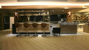 Une cuisine moderne avec un coin bar, un plancher en bois et un grand téléviseur.