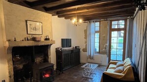 Un soggiorno rustico con travi a vista in legno, un camino, un divano e un televisore.