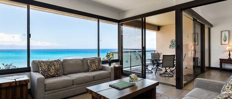 A modern living room with a sofa, coffee table, and a view of the ocean.