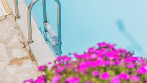 En swimmingpool med metallstegar och en gångväg av sten.