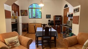 Una sala acogedora con dos sofás, una mesa de comedor y una cocina al fondo.
