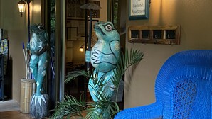 Una habitación con una silla azul, una escultura de rana y un cartel que dice 'The Hacienda Apartment'.
