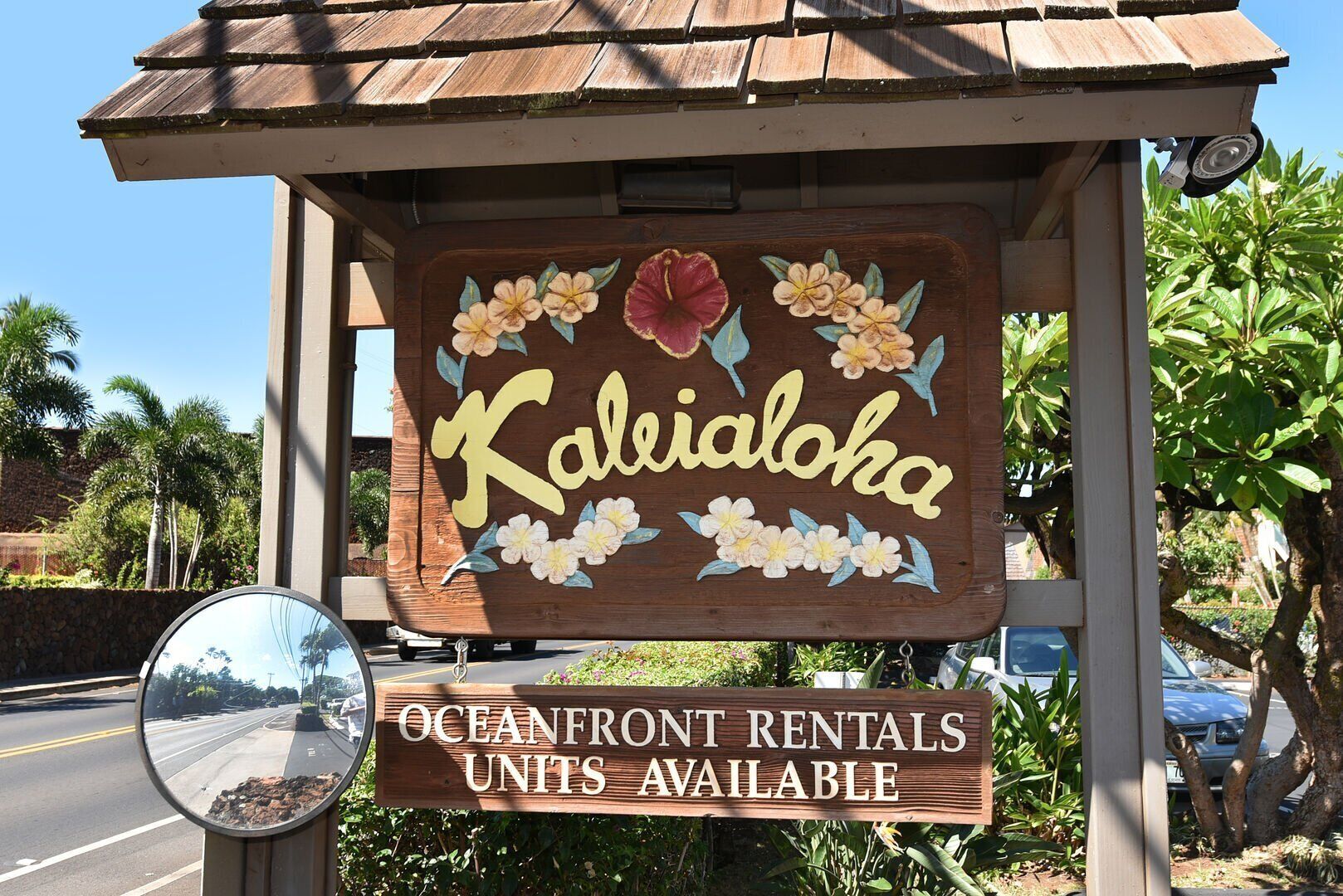 Un letrero de madera que dice 'Kailaloha' y 'Unidades de alquiler frente al océano disponibles', indicando una propiedad en alquiler.