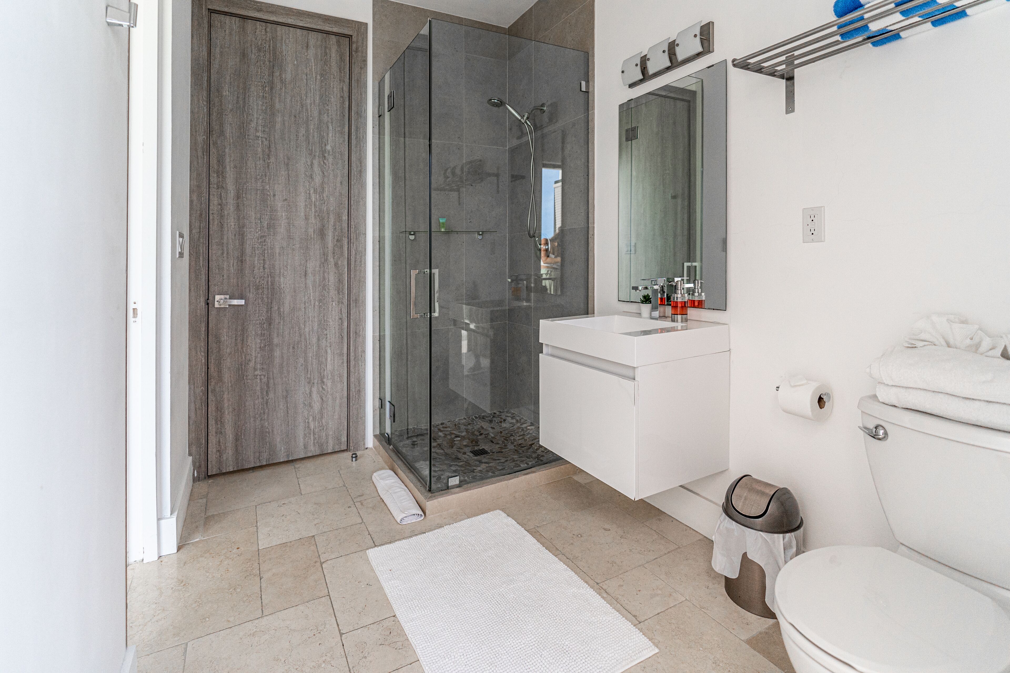 A modern bathroom with a glass shower enclosure, a white sink, and a toilet.